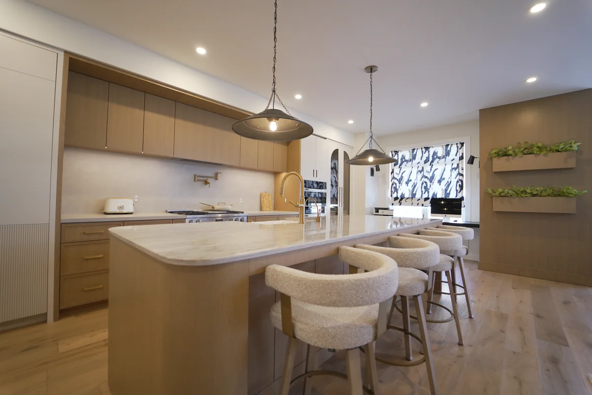 Warm wood kitchen with a pale stone island, rounded end and matching perimeter surfaces
