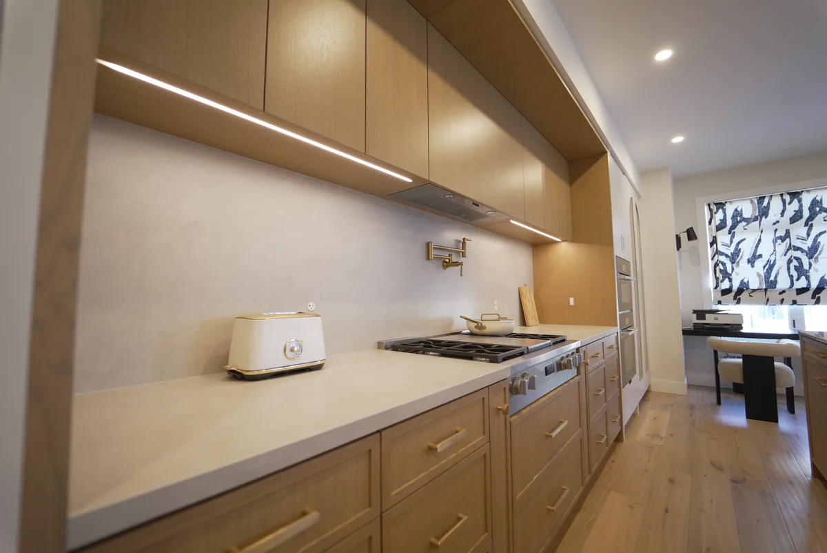Warm wood kitchen work wall with pale stone counters and backsplash