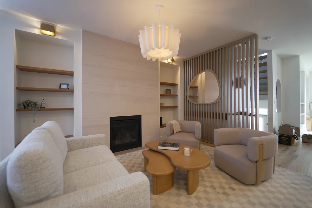Living room with a pale stone fireplace surround and warm vertical wood detailing
