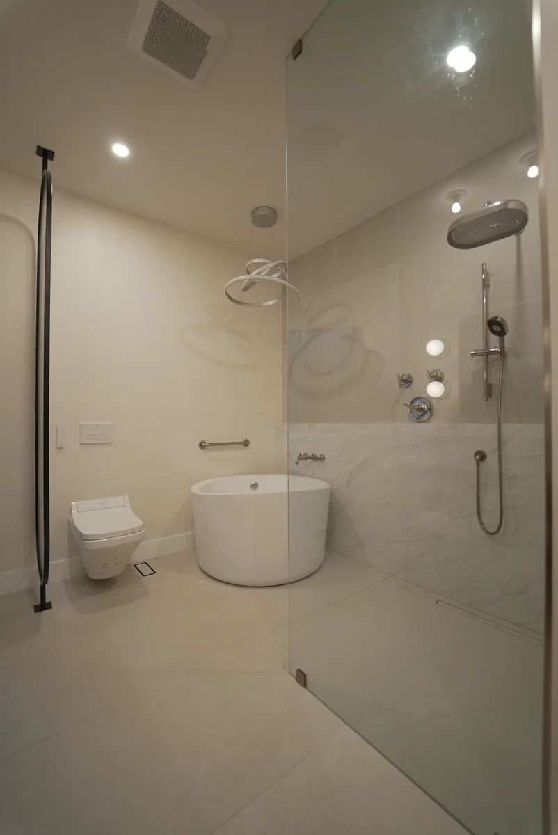 Bright bathroom with pale stone surfaces around the bathing area