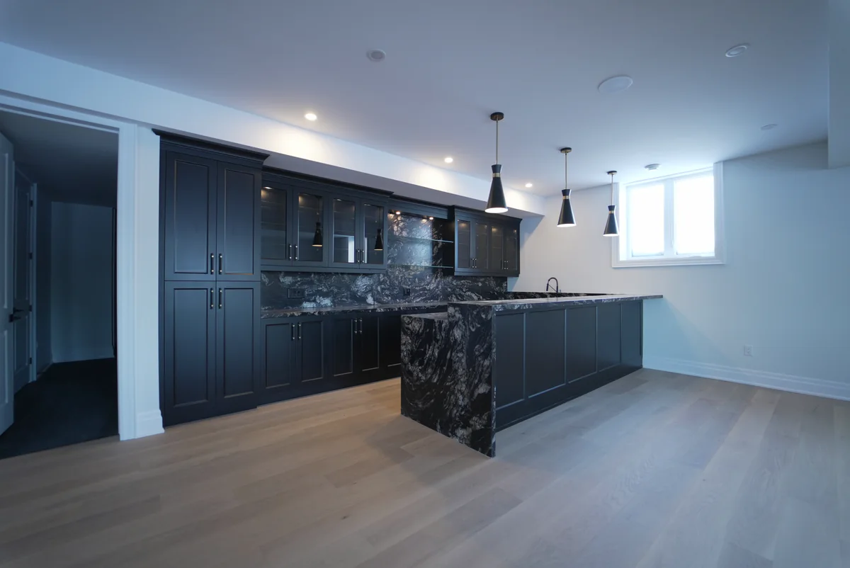 Dark cabinetry kitchen with a richly figured stone island and full-height backsplash