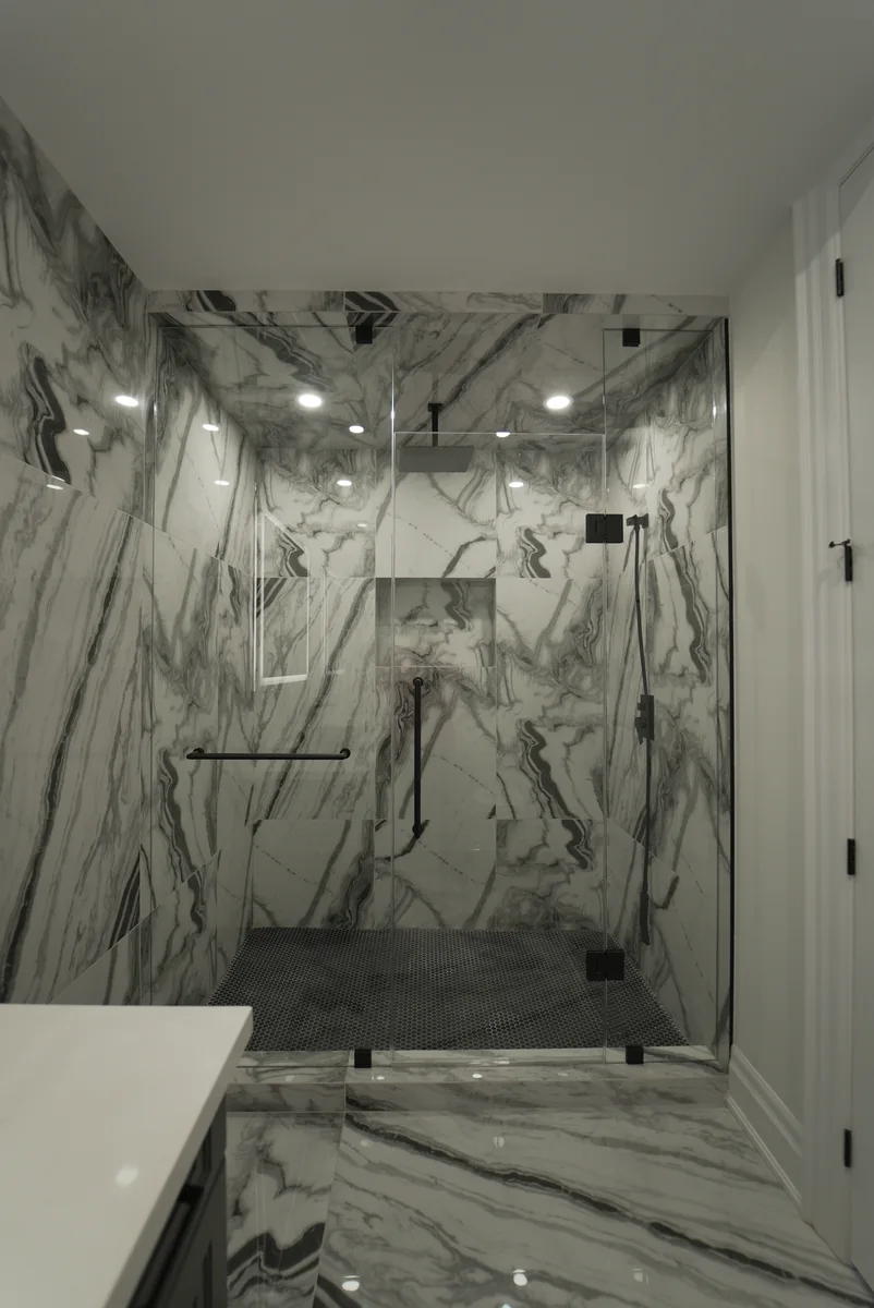 Glass shower with pale stone walls and carefully aligned veining