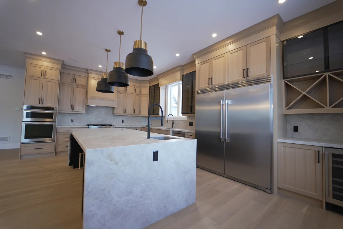 Light wood kitchen with a dark island wrapped in pale stone