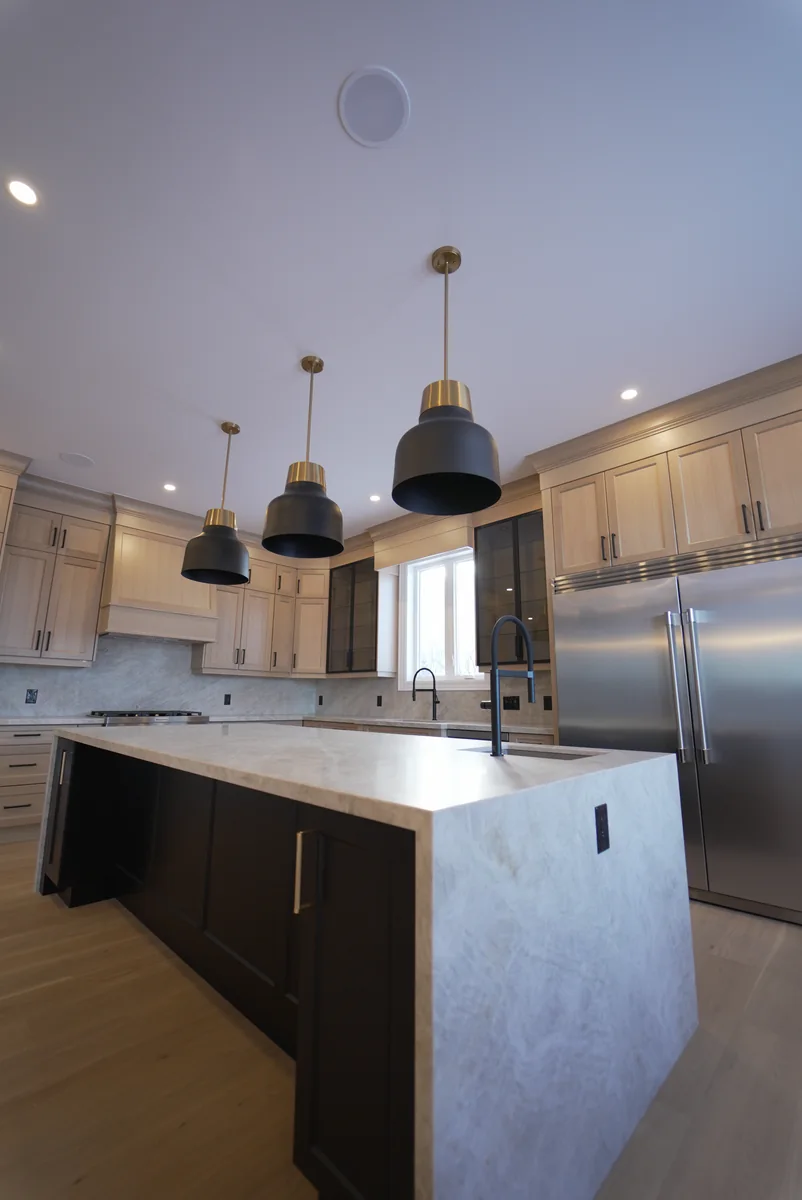 Close view of the pale stone island and waterfall edge beneath black pendants