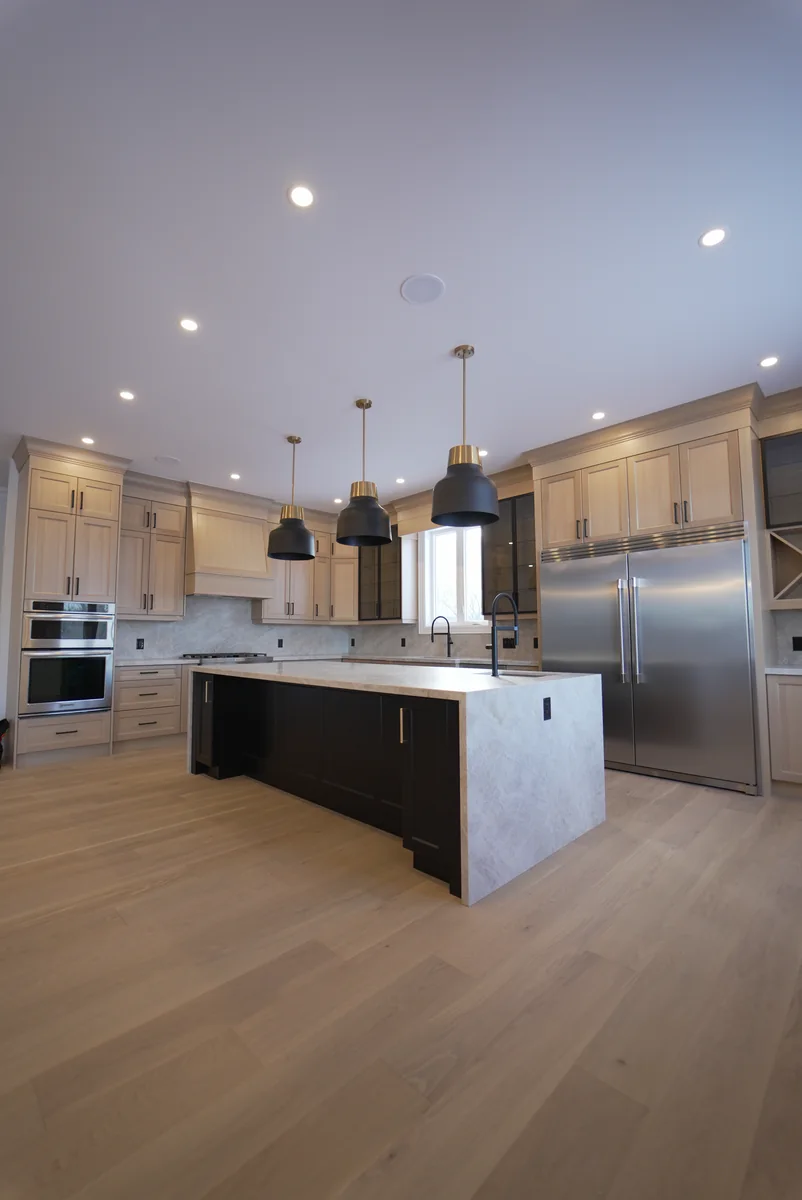 Full light wood kitchen with pale stone worktops and a dark central island
