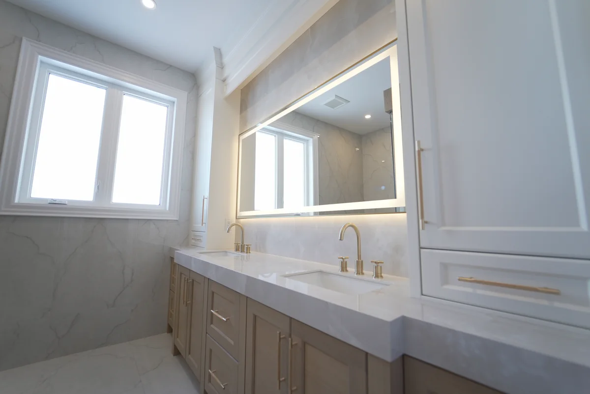 Bright bathroom with a long double vanity and pale stone counter and wall surfaces